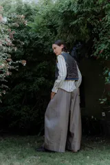 Chaleco de algodón color gris oscuro con bordados coloridos en contraste y ribetes en azul y amarillo. Presenta cierre frontal con tiras para atar.