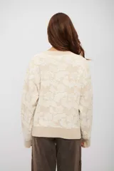 Saco tipo cardigan de punto con diseño floral en relieve, cuello en V y cierre frontal con botones. Presenta puños y ruedo acanalados.