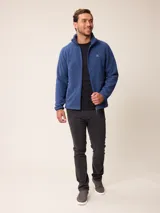 Campera de polar tipo sherpa en color azul, con cierre frontal completo, cuello alto y bolsillos laterales. Presenta un pequeño logo bordado en el pecho.