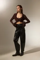 Pantalon de eco-cuero negro con acabado brillante, diseño tipo barrel de tiro alto, con bolsillos laterales y cierre frontal.