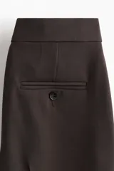 Pantalón tobillero de color marrón, con ajuste ceñido, raya frontal y posterior, cintura estándar, bolsillos al bies y piernas con corte bootcut.