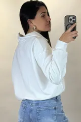 Buzo deportivo color blanco con cuello polo y cierre frontal parcial. Presenta mangas largas con puños elásticos y ruedo ajustable con cordón elástico.
