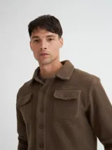 Camisaco color beige confeccionado en sherpa (corderito) con cartera de botones de pasta a tono y bolsillos con solapa en pecho.