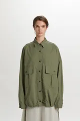 Campera bomber ligera color verde militar, confeccionada en 100% algodón, con bolsillos frontales con solapa, cierre de botones y cordón ajustable en el ruedo.