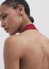 Top de punto fino con cuello halter y espalda descubierta con detalle de aro metálico. Diseño entallado sin mangas.