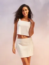 Musculosa corta de color blanco, confeccionada con mezcla de lino, con escote cuadrado y tirantes anchos.