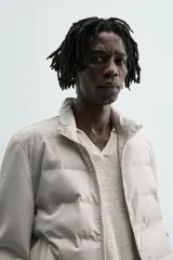 Cazadora acolchada de cuello subido, color negro, con mangas largas de tejido elástico. Incluye bolsillos en la cadera, un bolsillo interior y bajo con elástico. Cierre frontal de cremallera.