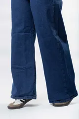 Pantalón de jean azul oscuro, tiro alto, de corte ancho (wide leg) y largo.