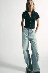 Camisa de denim entallada con cuello solapa, escote en pico y manga corta. Presenta costuras marcadas y cierre frontal con botones.