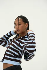 Campera con capucha de tejido de punto, color marrón oscuro y celeste, con diseño de rayas horizontales. Es de manga larga y cierre frontal con cremallera.