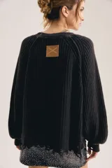 Sweater de punto grueso acanalado color negro, de corte oversized con mangas amplias y terminación deshilachada en el ruedo.