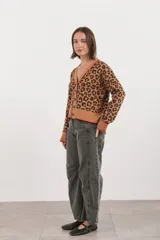 Saco de punto con estampado animal print, cuello en V y cierre frontal con botones. Presenta detalles de ribetes en color rojo en el cuello, puños y ruedo.