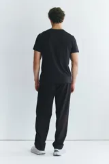 Pantalón deportivo negro de corte estándar y piernas rectas, confeccionado en tejido funcional ripstop con tecnología DryMove™. Cuenta con cintura elástica con cordón de ajuste oculto, bolsillos laterales con cierre y detalles perforados en las piernas.