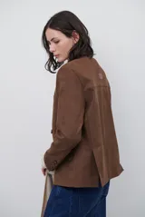 Blazer de gamuza color marrón, con solapas clásicas, cierre frontal de tres botones y bolsillos laterales con solapa.