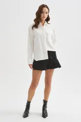 Camisa de viscosa blanca de corte holgado, con mangas largas, cuello camisero, cierre frontal con botones y detalle de bolsillo otonado en el pecho.