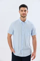 Camisa celeste de manga corta y corte slim fit, confeccionada en mezcla de lino y algodón. Presenta cuello camisero con botones, cierre frontal abotonado y un bolsillo aplicado en el pecho.
