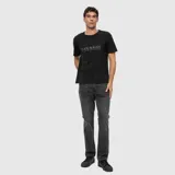 Remera blanca de corte regular con cuello redondo y mangas cortas. Presenta un estampado frontal con la frase 'BLACK IN BLACK' en color negro.