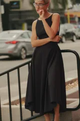 Vestido midi de gabardina en color negro, con cuello halter, tirantes finos y falda con vuelo. Cuenta con cierre en la espalda con cremallera oculta.