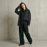 Camisa de corte oversize y diseño minimalista, confeccionada en tela fluida de color negro. Presenta cuello clásico, cierre frontal con botones ocultos y un bolsillo en el pecho.