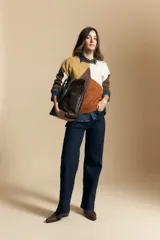 Sweater de tejido de punto con diseño geométrico de bloques de color en tonos tierra, marrón, ocre y blanco. Presenta cuello redondo, mangas largas y un corte relajado.