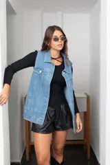Chaleco de jean largo con corte oversize, cierre frontal con botones metálicos, bolsillos laterales y bolsillos superiores con solapa.