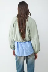 Campera de nylon manga larga en color verde militar, con cuello redondo, cierre frontal de cremallera y diseño fruncido con bajo elástico.