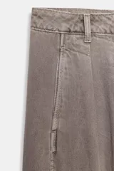 Jeans de tiro medio con corte wide leg y pernera ancha. Presenta pinzas delanteras, bolsillos frontales, bolsillos de plastrón en la espalda y cierre frontal con cremallera, botón interior y ganchos metálicos.