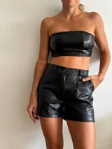 Short negro de cuero sintético con textura crocco, tiro alto, corte ajustado, bolsillos laterales y cierre frontal con botón.