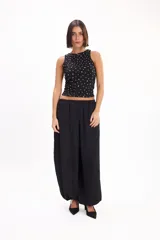 Pantalón marrón fluido de corte ancho y relajado, con cintura elástica fruncida y diseño abombado en las piernas.