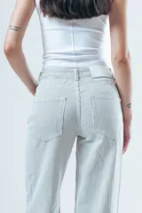 Pantalón de jean corte wide leg, color beige con estampado de rayas verticales finas. Presenta tiro alto, cierre frontal con botón y bolsillos laterales.
