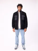 Campera reversible de sherpa y nylon, color negro, con cierre frontal, cuello alto y bolsillos frontales con solapa.