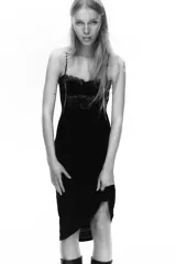 Vestido midi negro con escote recto y tirantes finos ajustables. Presenta un cuerpo superior con detalle de encaje floral y copas estructuradas, mientras que la falda es de corte recto y tejido liso.