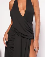 Vestido largo negro con escote halter cruzado y tajo lateral pronunciado.