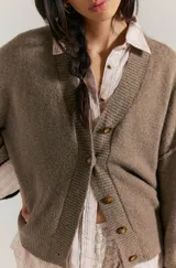 Cárdigan de punto marrón, con escote en V, hombros caídos y botones frontales.