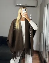 Poncho de tejido suave color blanco, con diseño abierto y flecos en el ruedo inferior.