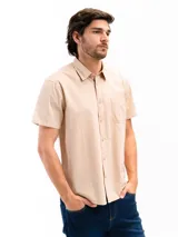 Camisa de manga corta color celeste claro, confeccionada en algodón, con cuello clásico y un bolsillo de parche en el lado izquierdo del pecho.