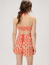 Top halter estampado en tonos rojo y beige, con tirantes finos ajustables al cuello y detalle de cuentas.