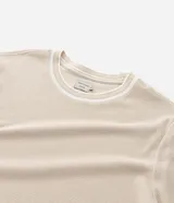 Remera de corte regular confeccionada en tejido de algodón texturizado, con cuello redondo y detalles de rayas contrastantes en cuello y mangas.