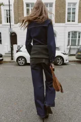 Camisa entallada de denim azul oscuro con cuello solapa, manga larga y cierre frontal con botones metálicos. Presenta un bolsillo de plastrón en el pecho y costuras a contratono.