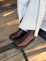 Bota corta de cuero en tonos chocolate, con diseño de paneles texturizados y suela track robusta de goma.