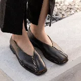 Zapato bajo de cuero negro con punta cuadrada y detalle de cierre en la capellada.