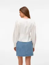 Blusa blanca de manga larga con cuello en V y cierre frontal de botones. Presenta mangas con volumen y puños abotonados, confeccionada en tejido plano.