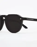 Gafas de sol Hawkers modelo Warwick, unisex, con montura geométrica negra y lentes polarizadas negras.