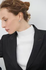 Blazer de corte sastrero en color gris oscuro, con cierre frontal de un botón, solapas clásicas y bolsillos con solapa. Presenta una estructura entallada y hombreras marcadas.