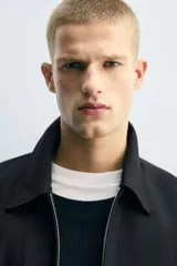 Cazadora de corte relajado confeccionada en tejido con estructura de espiga. Presenta cuello solapa, cierre frontal con cremallera, bolsillos de vivo en la cadera y bajo con pliegues en delantero y espalda.