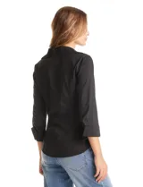 Camisa entallada de color negro con pechera estructurada mediante alforzas horizontales. Presenta cuello con solapa, escote en V, cierre frontal con botones y mangas tres cuartos con puños anchos rebatibles.