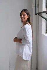Remera de algodón color blanco, con cuello en V, mangas largas y corte holgado con costuras visibles en el ruedo.