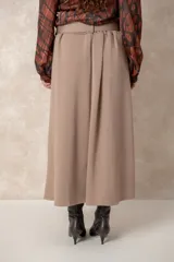 Pollera midi de corte acampanado y tiro alto, con diseño plisado en la cintura y bolsillos laterales. Confeccionada en tela de textura suave color beige.