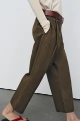 Pantalón cropped de tiro medio con diseño de pinzas en el delantero, bolsillos laterales y bolsillos de vivo en la parte trasera. Cuenta con trabillas en la cintura y cierre frontal con cremallera y botón.