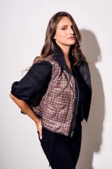 Chaleco negro con cierre frontal y cuello alto, de corte al cuerpo y diseño acolchado. Reversible, con interior a cuadros.